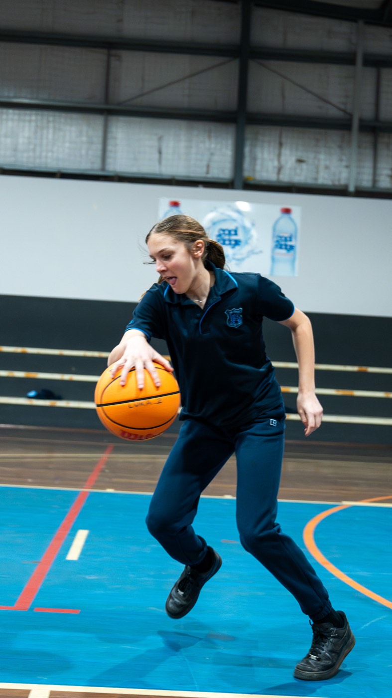 Student dribbling a basketball up the court